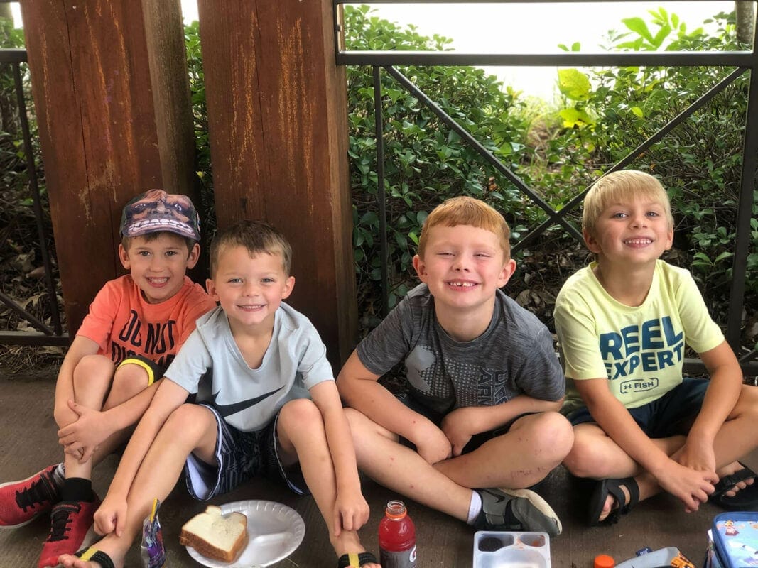 4 Boys sitting outside in a row smiling